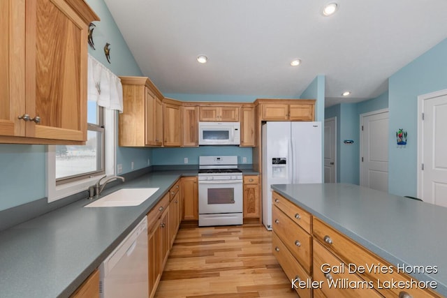 kitchen with white appliances, dark countertops, light wood-type flooring, a sink, and recessed lighting