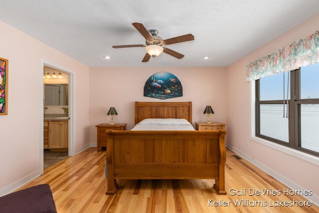 bedroom featuring connected bathroom, light wood-style flooring, and baseboards