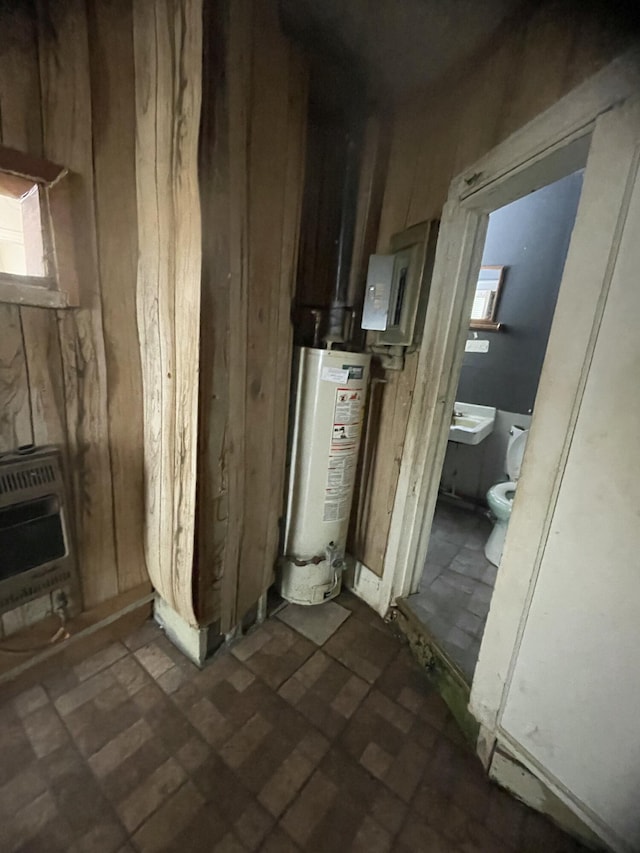 utility room featuring heating unit, electric panel, and gas water heater