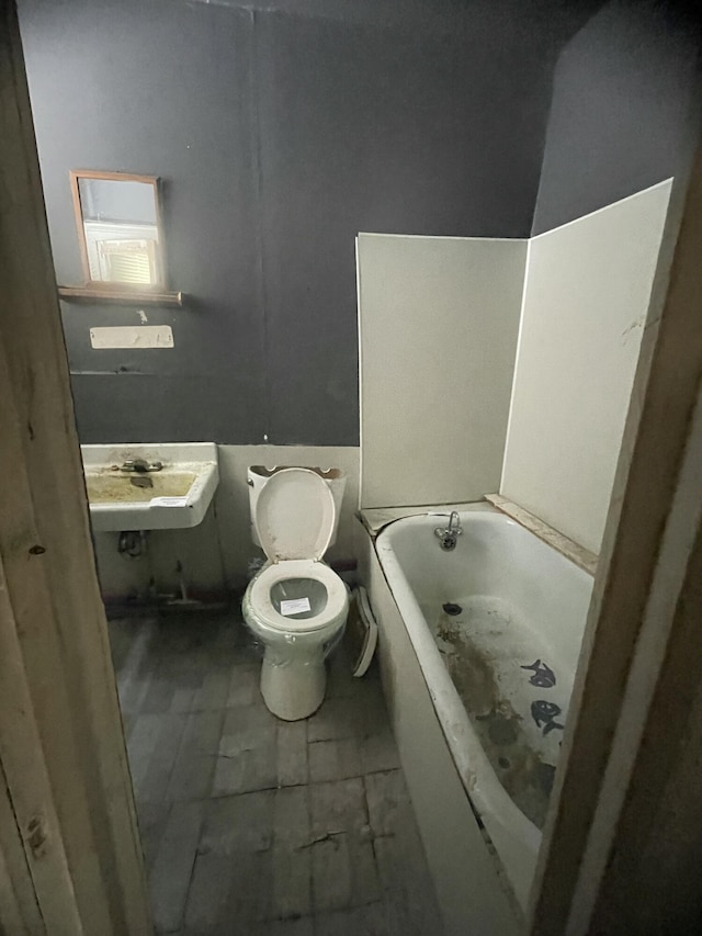 bathroom with sink, a bathing tub, and toilet