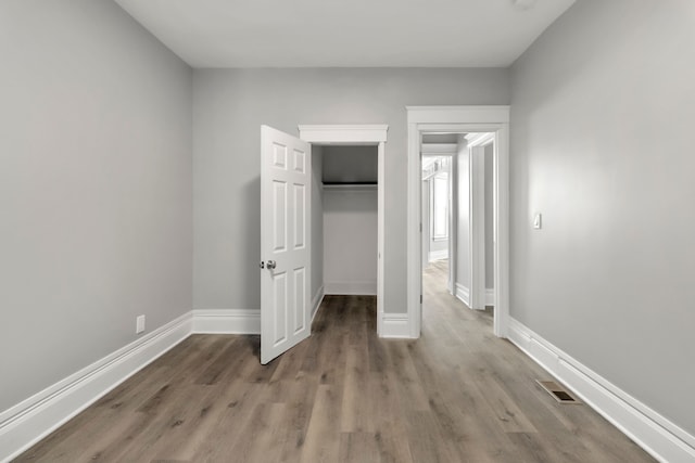 unfurnished bedroom with a closet, a walk in closet, and light hardwood / wood-style floors