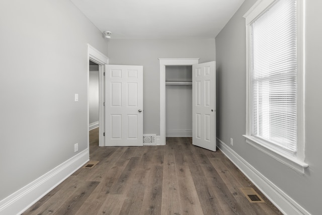 unfurnished bedroom with a closet and dark wood-type flooring