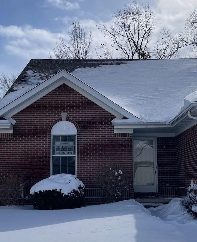 view of snowy exterior featuring brick siding