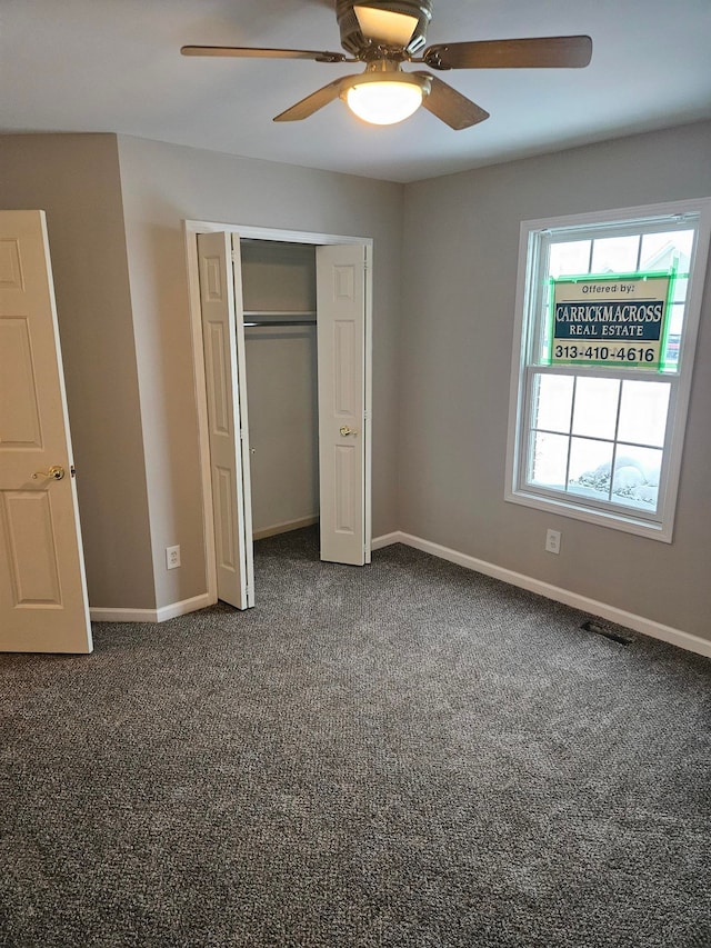 unfurnished bedroom featuring a closet, visible vents, dark carpet, ceiling fan, and baseboards