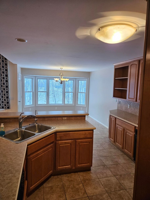 kitchen featuring brown cabinetry, hanging light fixtures, light countertops, open shelves, and a sink