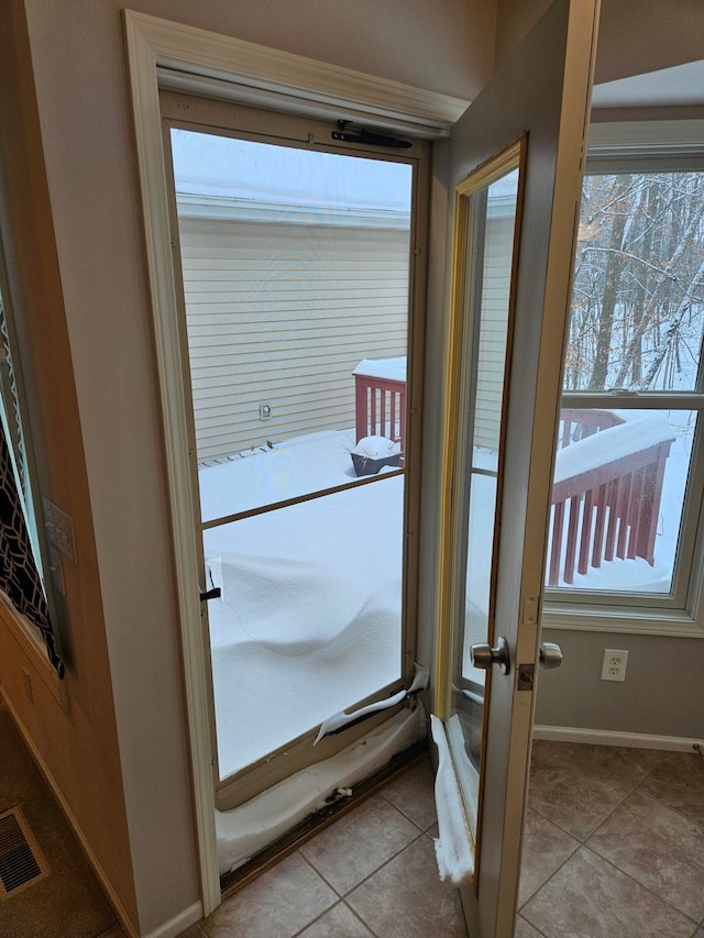 doorway to outside with light tile patterned floors, plenty of natural light, visible vents, and baseboards