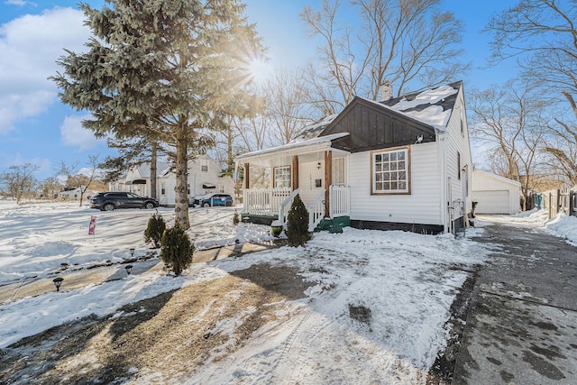 view of front of property with covered porch, a detached garage, and an outdoor structure