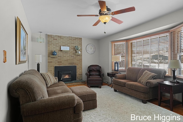 living room featuring a brick fireplace, ceiling fan, and wood-type flooring