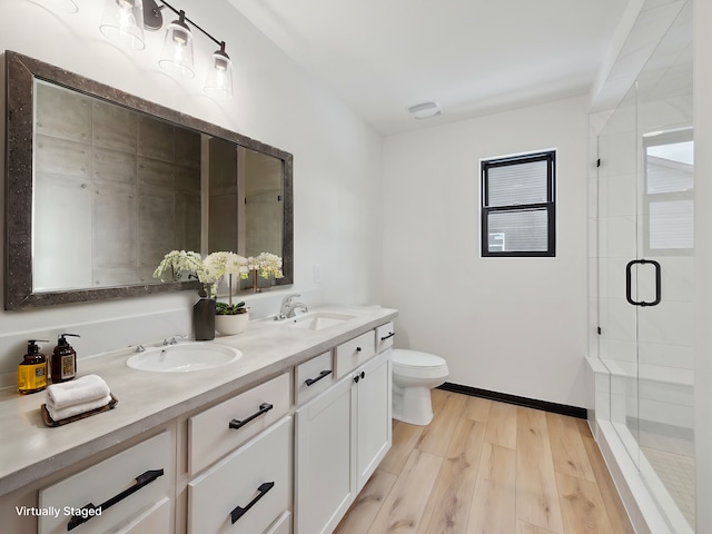 full bath featuring toilet, a stall shower, a sink, and wood finished floors