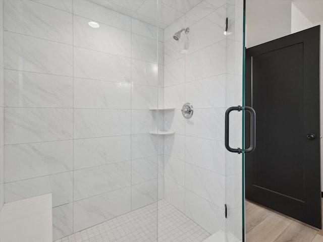 bathroom with wood finished floors and a shower stall