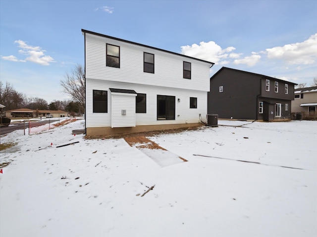 snow covered rear of property featuring central AC