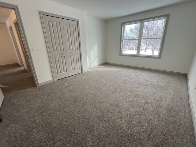 unfurnished bedroom featuring a closet, baseboards, and carpet flooring