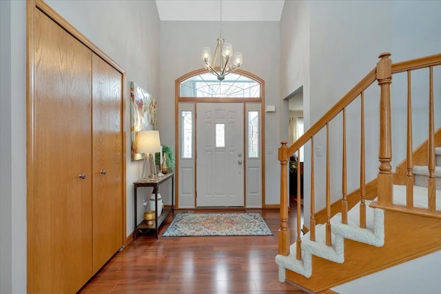 foyer featuring a notable chandelier, dark wood finished floors, a towering ceiling, baseboards, and stairs