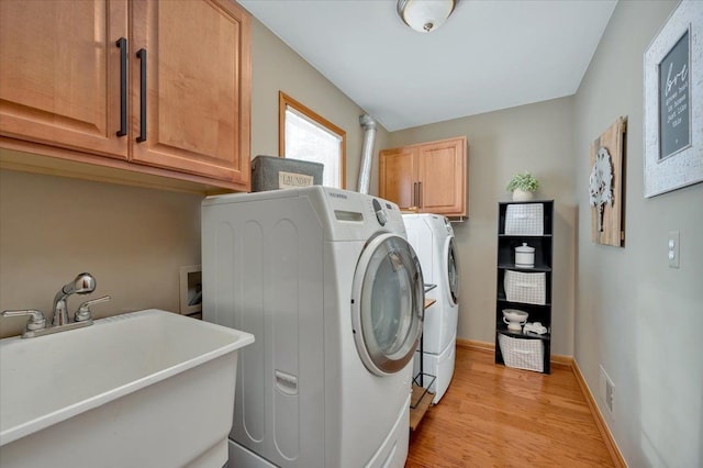 washroom with a sink, visible vents, baseboards, cabinet space, and washer and clothes dryer