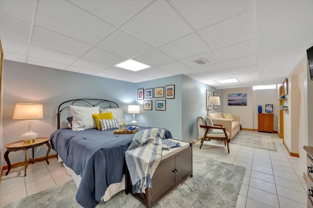 bedroom featuring light tile patterned floors, a paneled ceiling, visible vents, and baseboards