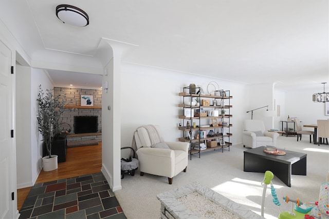 carpeted living room featuring a fireplace and an inviting chandelier