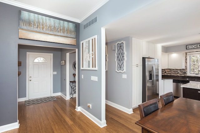 entrance foyer featuring dark wood-style floors, visible vents, crown molding, and baseboards