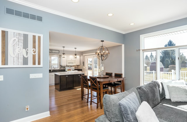 dining space with visible vents, wood finished floors, recessed lighting, crown molding, and a chandelier