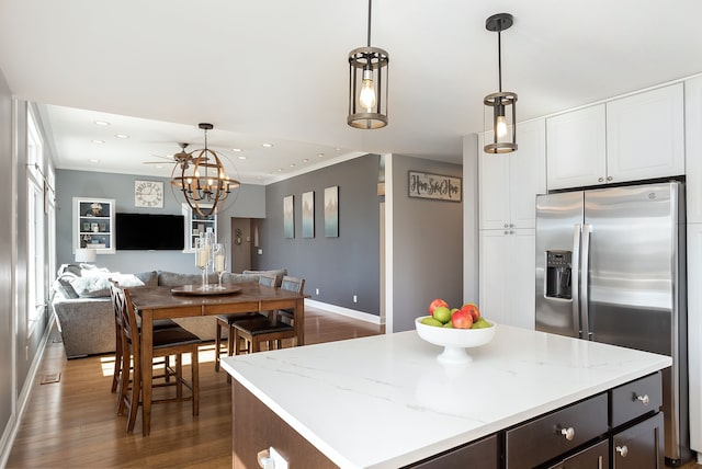 kitchen with wood finished floors, ornamental molding, stainless steel fridge, pendant lighting, and open floor plan