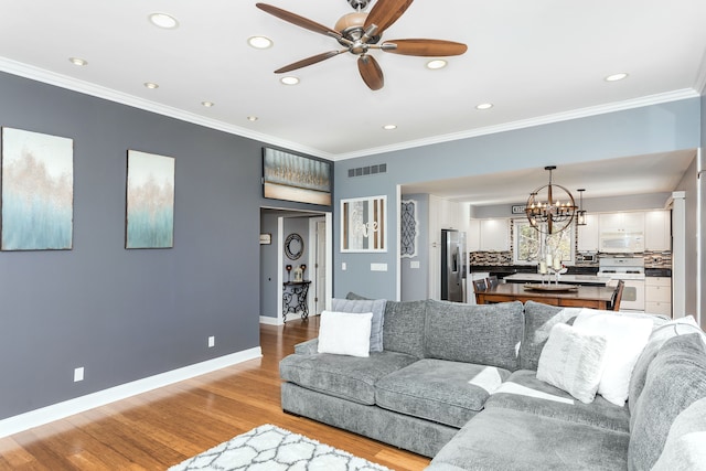 living room with visible vents, wood finished floors, baseboards, and ornamental molding