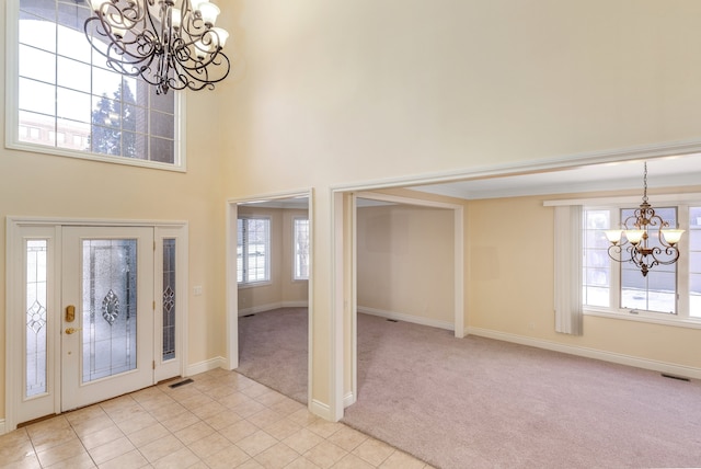 entrance foyer featuring light carpet, light tile patterned floors, visible vents, a towering ceiling, and a chandelier