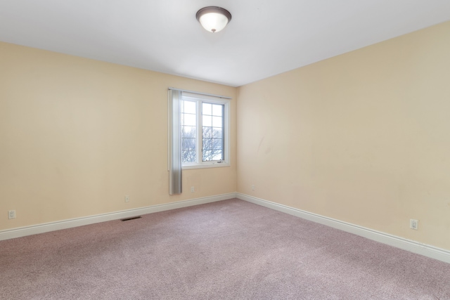 carpeted spare room with visible vents and baseboards