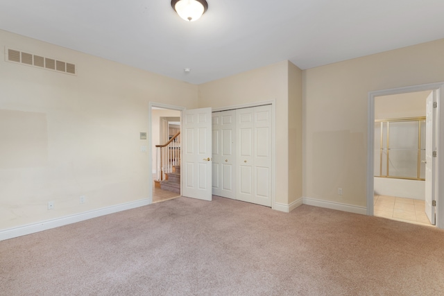 unfurnished bedroom featuring baseboards, visible vents, a closet, and light colored carpet