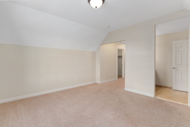 additional living space featuring light carpet, lofted ceiling, and baseboards