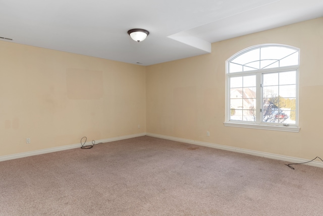 empty room featuring light carpet and baseboards