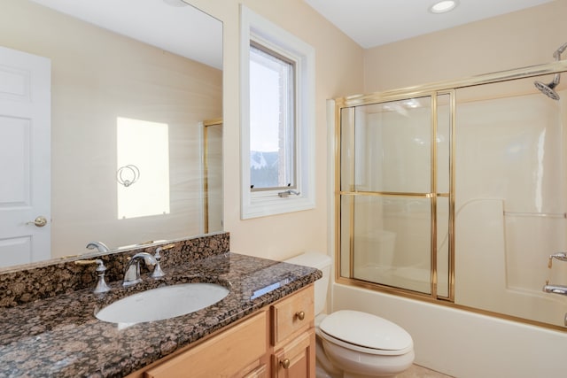 full bath with toilet, bath / shower combo with glass door, and vanity