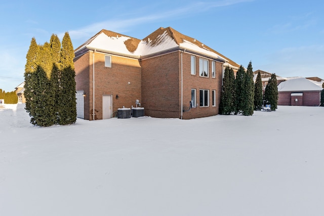 exterior space with a garage, brick siding, and central air condition unit