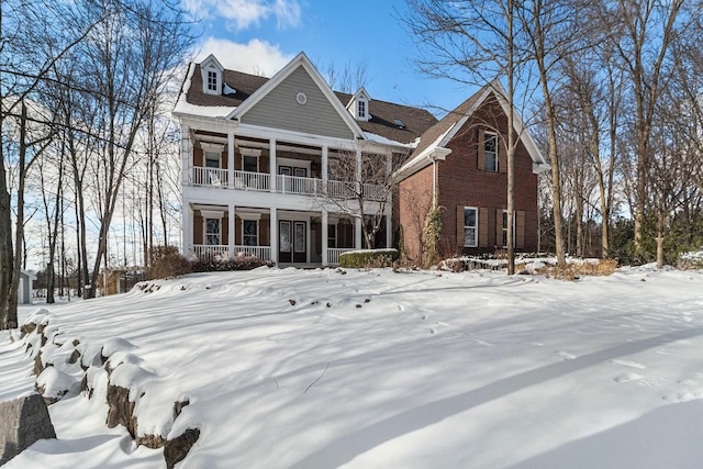 view of front of house featuring a balcony, covered porch, and brick siding