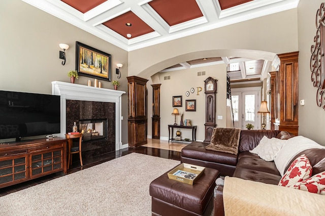 living area with beam ceiling, arched walkways, coffered ceiling, and crown molding