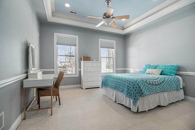 carpeted bedroom with ornamental molding, a tray ceiling, visible vents, and baseboards