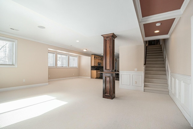 unfurnished living room with decorative columns, a decorative wall, crown molding, and light colored carpet