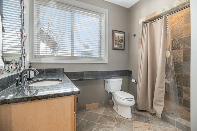 bathroom with toilet, stone finish floor, a stall shower, and vanity