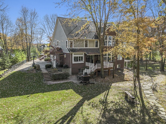 back of property featuring brick siding, stairs, a lawn, and a patio