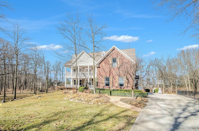 view of front of house featuring concrete driveway, a balcony, and a front lawn