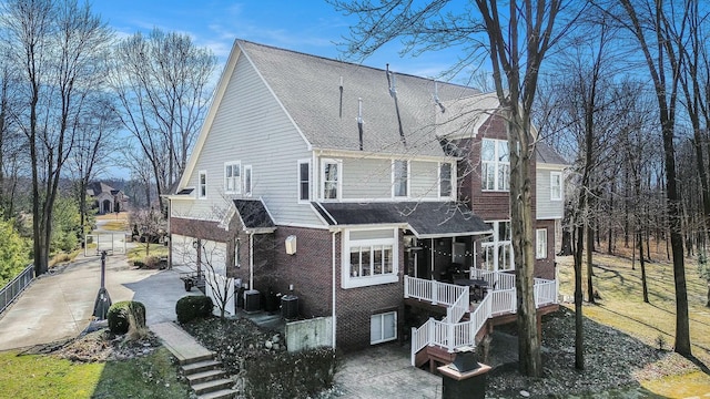 rear view of house with stairs, cooling unit, and brick siding