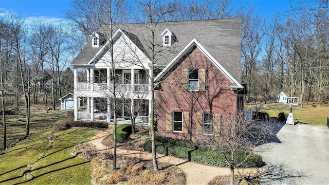 view of front of property featuring an outbuilding, driveway, a front lawn, a porch, and a balcony