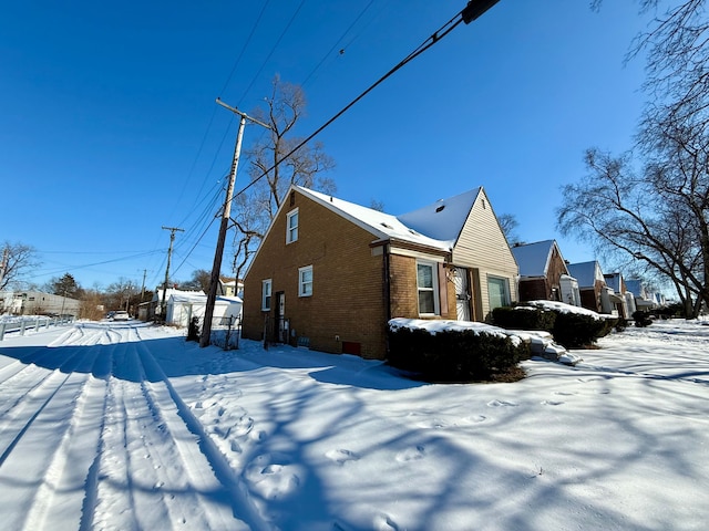 snow covered property with a garage and brick siding