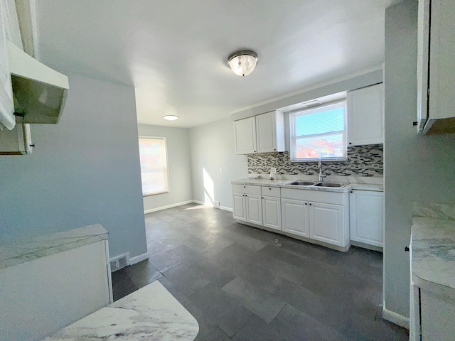 kitchen featuring plenty of natural light, light countertops, a sink, and decorative backsplash