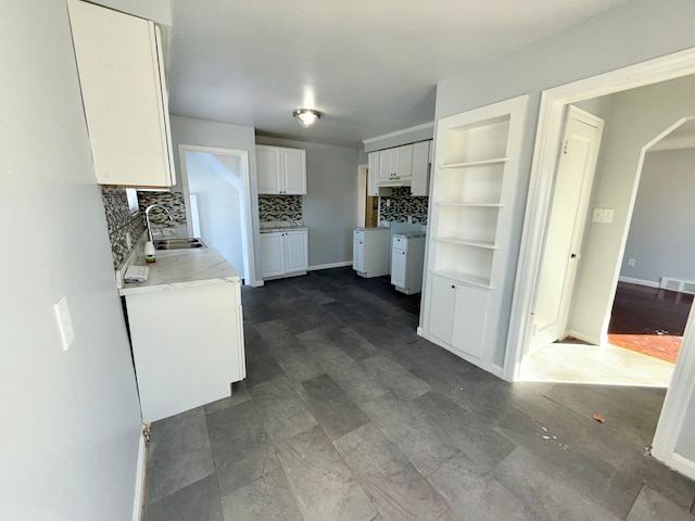 kitchen featuring visible vents, arched walkways, a sink, white cabinetry, and backsplash