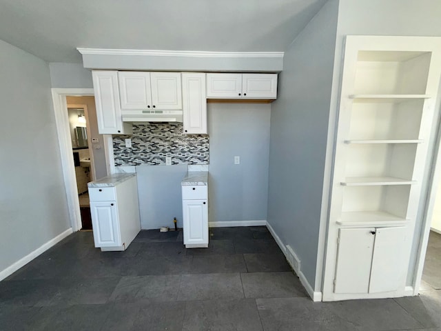 kitchen with built in shelves, tasteful backsplash, light countertops, white cabinets, and under cabinet range hood