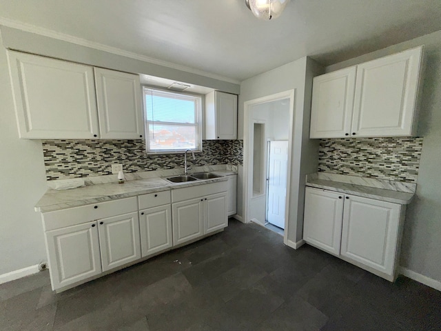 kitchen featuring baseboards, white cabinetry, light countertops, and a sink