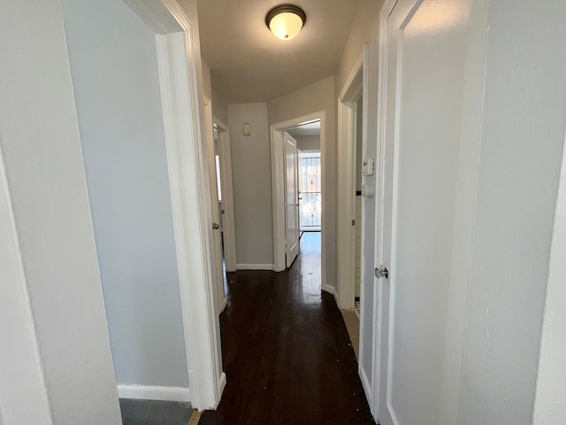 hallway featuring baseboards and dark wood finished floors