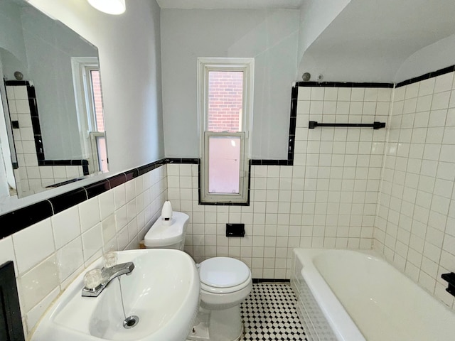 full bathroom featuring tile walls, toilet, a bathing tub, a sink, and tile patterned floors