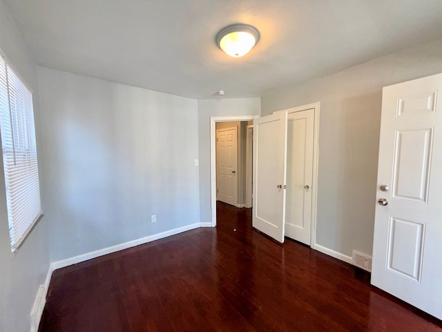 unfurnished bedroom featuring a closet, wood finished floors, visible vents, and baseboards