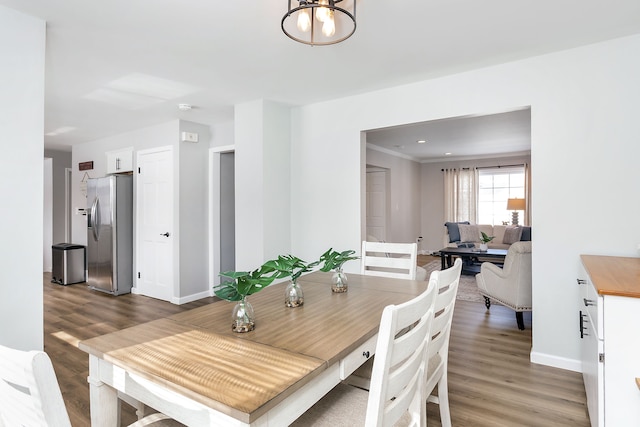 dining area with ornamental molding, a chandelier, baseboards, and wood finished floors