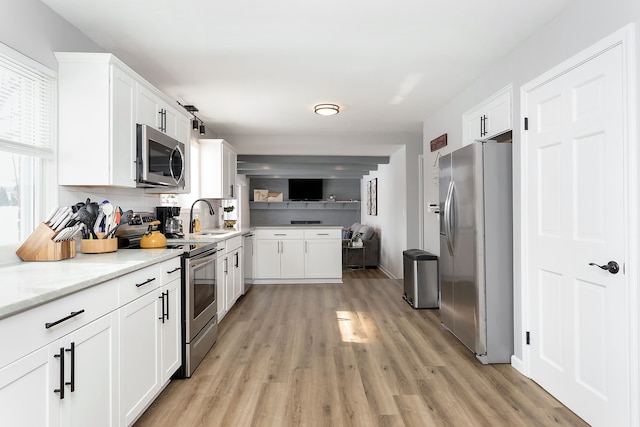 kitchen featuring stainless steel appliances, a sink, white cabinetry, and light wood-style floors